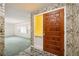 Inviting foyer with a striking wood door, decorative wallpaper, and tile flooring, leading to a living area at 180 Broadmoor Rd, Lake Mary, FL 32746
