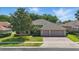 Charming single-story home boasts a manicured lawn, mature trees, and a three-car garage, creating a welcoming curb appeal at 2391 Northumbria Dr, Sanford, FL 32771