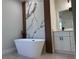 Modern bathroom featuring a freestanding tub with black fixtures and a decorative marble accent wall at 2406 Sw 163Rd Pl, Ocala, FL 34473