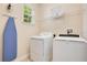 Well-lit laundry room with appliances, storage shelves, and an ironing board for convenience at 7644 Fairfax Dr, Kissimmee, FL 34747