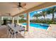 Covered patio dining area with a view of the pool and spa surrounded by palm trees at 7644 Fairfax Dr, Kissimmee, FL 34747