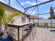 Outdoor pool bar with a granite countertop, stone accents, seating, and a screened enclosure for year-round enjoyment at 826 Jade Forest Ave, Orlando, FL 32828