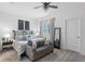 Well-lit main bedroom featuring a plush bed, ceiling fan, and gray loveseat at 308 Rustic Loop, Sanford, FL 32771