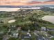 Aerial view features a golf course, lake, and surrounding homes in a serene, picturesque neighborhood setting at sunset at 6054 Tarawood Dr, Orlando, FL 32819