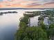 A picturesque aerial view showcases a serene lake with boats docked, framed by lush trees and waterfront properties at sunset at 6054 Tarawood Dr, Orlando, FL 32819