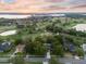 Stunning aerial view of a beautiful home overlooking a lush golf course and serene lake at sunset at 6054 Tarawood Dr, Orlando, FL 32819