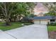 Beautiful home featuring a large driveway, side-entry garage, mature trees, and landscaping at 6054 Tarawood Dr, Orlando, FL 32819