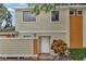 Two-story townhome featuring a white door, beige stucco and orange wood facade, and a well-kept yard at 66 Silver Falls Cir, Kissimmee, FL 34743