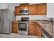 Clean kitchen featuring stainless steel appliances, granite countertops, and light brown cabinets at 66 Silver Falls Cir, Kissimmee, FL 34743