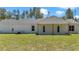 Backyard view featuring a white home with a covered patio and an expansive green lawn at 6725 Sw 131St Cir, Ocala, FL 34481