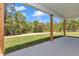 View of the green yard and woods from the covered patio with stained wood posts and white ceiling at 6725 Sw 131St Cir, Ocala, FL 34481