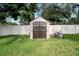 Backyard shed with a wooden door and white trim surrounded by a green lawn and white fence at 819 Haulover Dr, Altamonte Springs, FL 32714