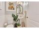 Charming powder room with pedestal sink, beadboard walls, decorative mirror, and tropical artwork at 12636 Hammock Pointe Cir, Clermont, FL 34711