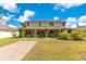 Two-story home with a spacious lawn, inviting porch with decorative plants, and solar panels on the roof at 12636 Hammock Pointe Cir, Clermont, FL 34711