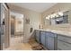 Stylish bathroom with blue vanity, granite countertops, decorative mirrors, and soaking tub in the background at 14037 Fairway Willow Ln, Winter Garden, FL 34787