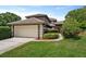 Home featuring a two-car garage, well-maintained lawn, tile roof, and inviting front entrance at 14037 Fairway Willow Ln, Winter Garden, FL 34787