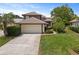 Beautiful home with a large driveway, two-car garage, lush landscaping, and tile roof at 14037 Fairway Willow Ln, Winter Garden, FL 34787