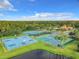 A bird's eye view of tennis and basketball courts surrounded by trees and a pond at 14137 Queenside St, Orlando, FL 32824