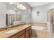 Well-lit bathroom featuring double sinks, a large mirror, a tub, and a glass door shower at 14137 Queenside St, Orlando, FL 32824