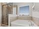 Elegant bathroom features a soaking tub with a window view and a glass-enclosed shower at 16124 Azure Key St, Winter Garden, FL 34787
