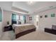 Well-lit bedroom with a tray ceiling, neutral decor, and a view into an ensuite bathroom at 16124 Azure Key St, Winter Garden, FL 34787