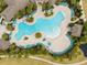 Aerial view of a unique, cloud-shaped pool surrounded by greenery, lounge chairs, and walkways at 16124 Azure Key St, Winter Garden, FL 34787