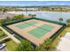 Aerial view of tennis courts with green fencing surrounded by palm trees, lawns and sidewalks at 16124 Azure Key St, Winter Garden, FL 34787