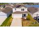 Aerial view of two-story home boasting solar panels, attached garage, manicured lawn, and nearby lake at 2294 Canyon Breeze Ave Ave, Kissimmee, FL 34746