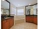 Bright bathroom features a soaking tub, dark granite counters, and warm cabinetry at 2365 Sterling Creek Pkwy, Oviedo, FL 32766