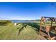 Lakeside backyard featuring a wooden swing set and views of the lake and wooden pier at 241 Lake Thomas Dr, Winter Haven, FL 33880