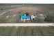 Aerial view of a rural home with a blue roof, adjacent to a dirt road and expansive fields at 270 S Lake Patrick Rd, Frostproof, FL 33843