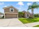 Inviting exterior featuring a two-story home with lush green lawn and meticulously landscaped front yard with palm trees at 2787 Cypress Head Trl, Oviedo, FL 32765