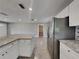 View of the kitchen with stainless steel refrigerator, granite counters, and view to the living area at 3220 Mahalia Pl, Orlando, FL 32805
