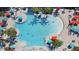 Overhead view of a large, bright blue swimming pool with colorful umbrellas and lounge chairs surrounding it at 3806 Lana Ave, Davenport, FL 33897