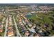 A distant aerial view of a neighborhood with a pond, trees, and grassland behind a road at 5270 Wildwood Way, Davenport, FL 33837