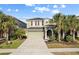 Inviting two-story home featuring a well-manicured lawn, mature palm trees and a neutral color palette at 5270 Wildwood Way, Davenport, FL 33837