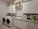 A well-equipped laundry room featuring a washer, dryer, sink, and storage cabinets for added convenience at 603 Sanctuary Golf Pl, Apopka, FL 32712