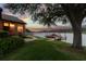 Scenic backyard view featuring a lush lawn, a charming house, and a covered boat dock on the lake at 616 Grand Cypress Pt, Sanford, FL 32771