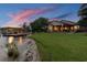 Picturesque waterfront backyard featuring a lush lawn leading to the water's edge and a covered boat dock at 616 Grand Cypress Pt, Sanford, FL 32771