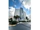 Beautiful condominium building with manicured landscaping, palm trees, and sunny skies at 6165 Carrier Dr # 2308, Orlando, FL 32819
