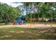 A colorful community playground with slides and swings surrounded by a lush green lawn and mature trees at 6550 Crestmont Glen Ln, Windermere, FL 34786