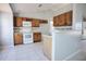 Functional kitchen featuring wood cabinetry, white appliances, and breakfast bar overlooking living area at 7700 Greytwig Ln, Orlando, FL 32818