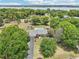 This single Gathering home in an aerial view, showing the lake in the distance, featuring a pool and gazebo nestled in a tree filled yard at 7779 Lake Andrea Cir, Mount Dora, FL 32757