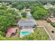 Aerial shot exhibits a single-Gathering home boasting a pool and gazebo, set against a backdrop of lake views and lush greenery at 7779 Lake Andrea Cir, Mount Dora, FL 32757