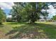 Large backyard with lush green grass, mature trees and a shed with a pool table on the porch at 7779 Lake Andrea Cir, Mount Dora, FL 32757