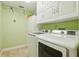 Bright laundry room with white cabinets, a modern washer and dryer, and clean, green walls at 7779 Lake Andrea Cir, Mount Dora, FL 32757