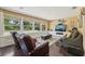 Bright living room featuring hardwood floors, plush seating, and wall-to-wall windows at 7779 Lake Andrea Cir, Mount Dora, FL 32757