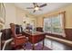 Bright home office with a dark wood desk, leather chair, and hardwood flooring at 7779 Lake Andrea Cir, Mount Dora, FL 32757