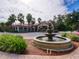 Charming exterior view of the clubhouse with a decorative fountain, palm trees, and landscaping at 8000 Tuscany Way # 4408, Davenport, FL 33896