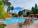 Resort-style pool area with lounge chairs, cabanas, and lush tropical landscaping under blue skies at 8000 Tuscany Way # 4408, Davenport, FL 33896